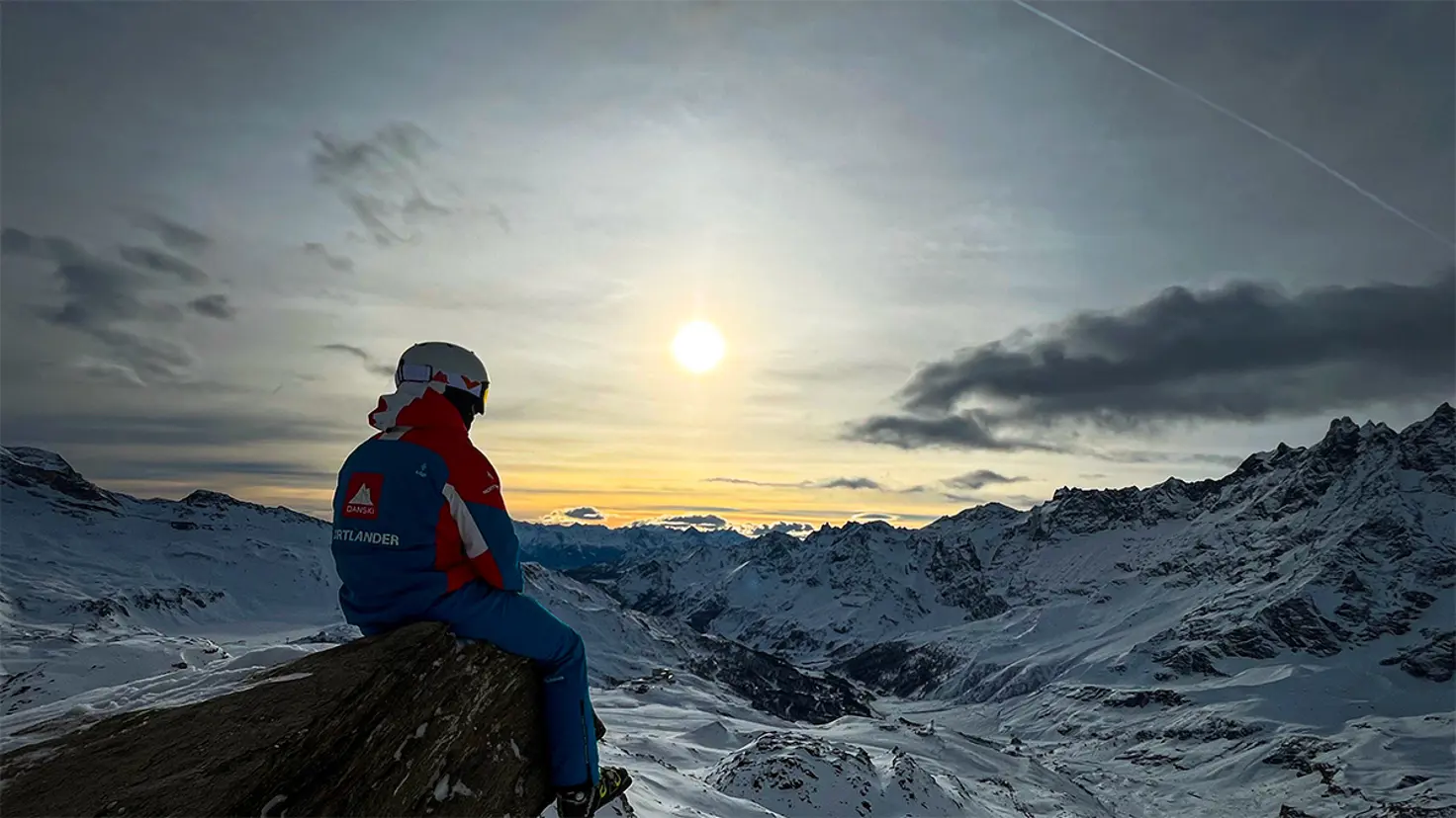 skiguide sidder og ser udover bjerge