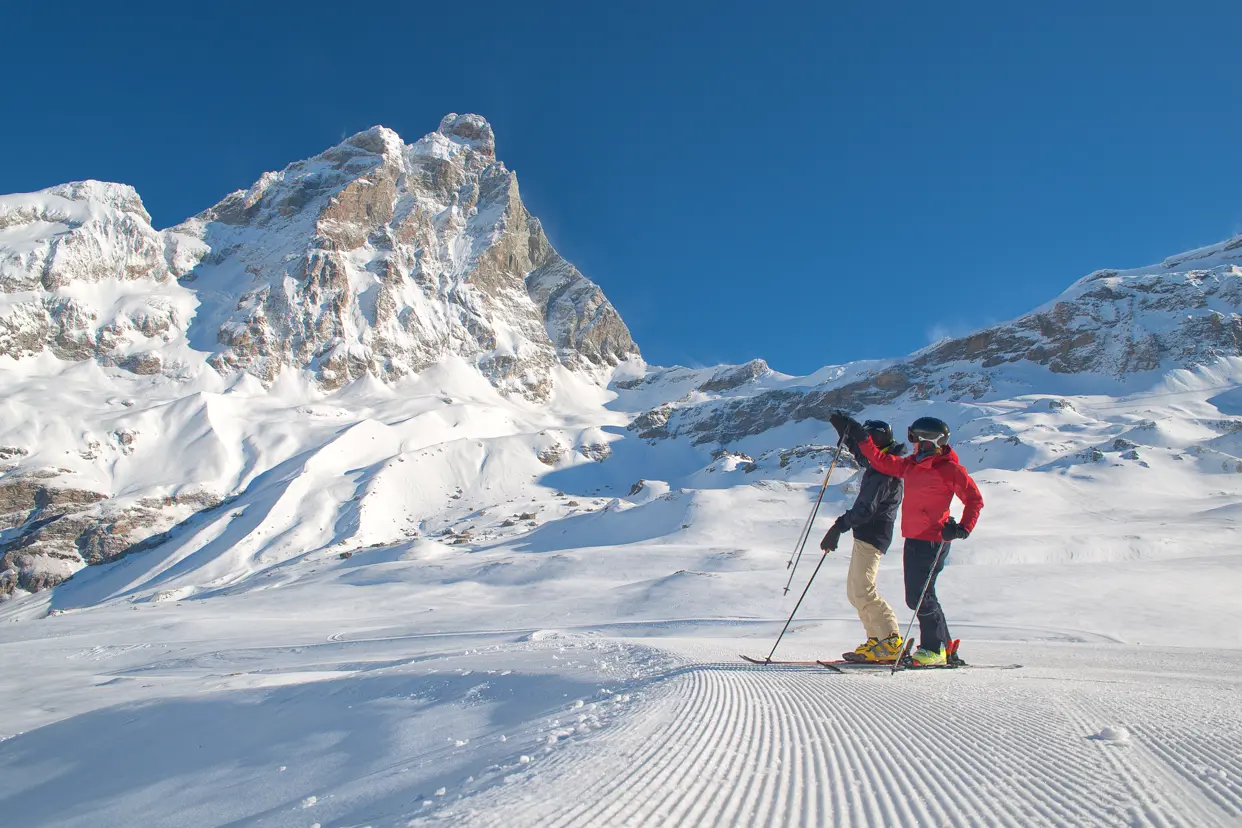 Cervinia är Italiens skidparadis, där två skidåkare står och beundrar den majestätiska utsikten över Matterhorn.