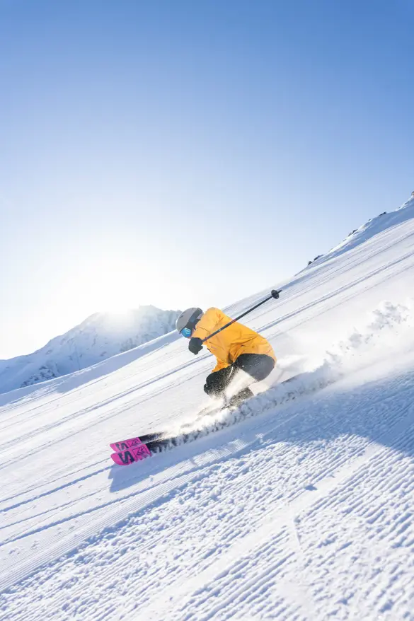 En skidåkare åker nerför en pistad backe i Val Thorens-Orelle, en del av de tre dalarna (Les 3 Vallées), omgiven av snötäckta berg.
