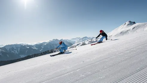 Skidåkare åker nerför en snöklädd skidbacke i Wagrain, Österrike, känd för sina fantastiska vinterförhållanden och alpin skidåkning.