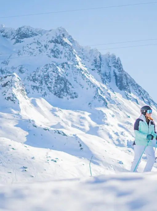 Tre skidåkare njuter av en härlig dag i backarna i Val Thorens-Orelle, omgiven av snötäckta berg och klart väder.