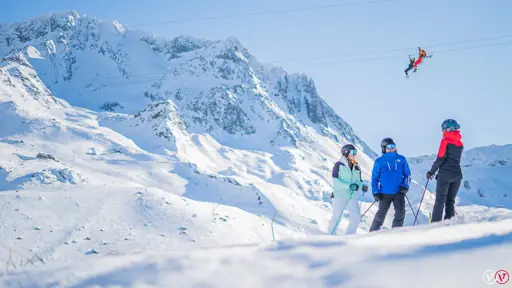 Tre skidåkare njuter av en härlig dag i backarna i Val Thorens-Orelle, omgiven av snötäckta berg och klart väder.