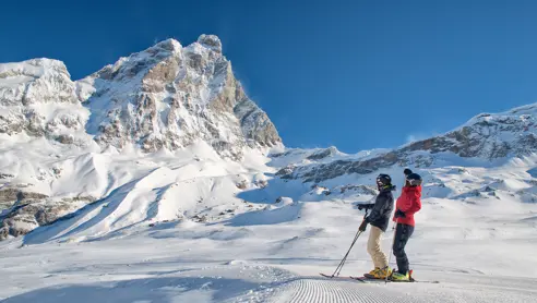 Två skidåkare blickar ut över skidsystemet i Breuil-Cervinia-Valtournenche, en populär skidort i Alperna, med Nortlander som erbjuder skidresor till regionen